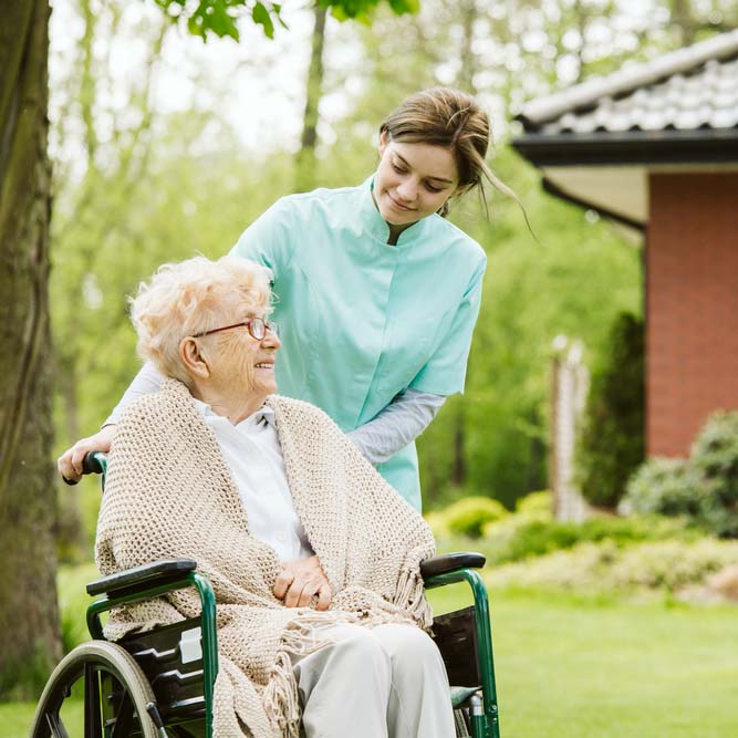 Professional caregiver smiling while assisting elderly woman